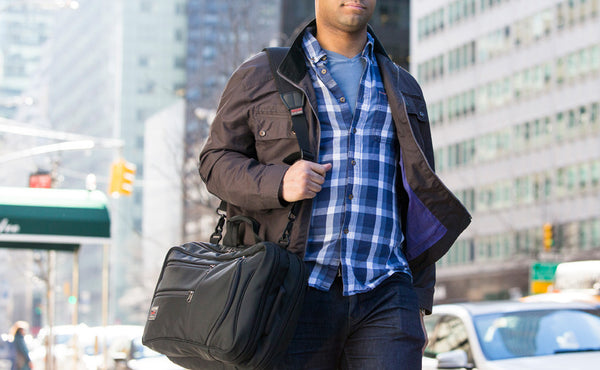 A person carrying a Black 525 Ballistic Western Flyer using the optional Absolute Shoulder Strap on a city street.